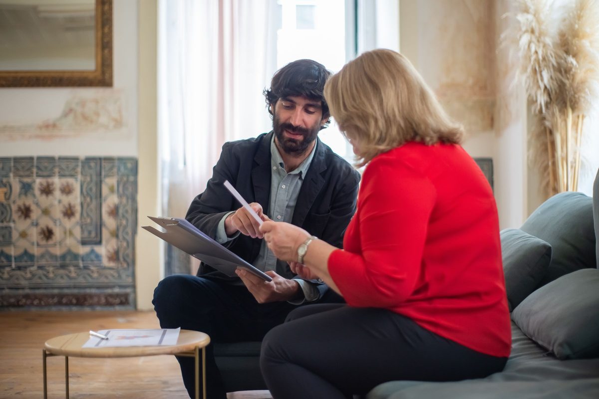An adviser and a client talking through papers on a sofa